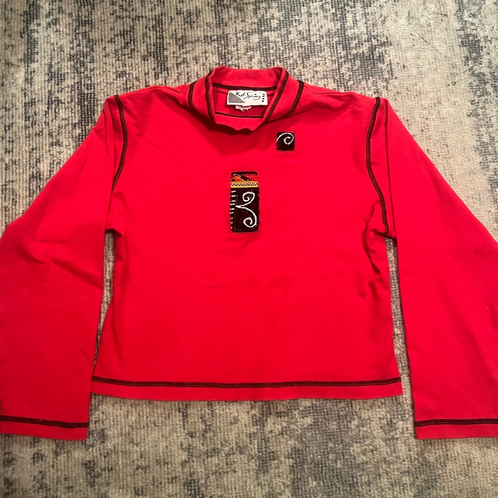 Red long sleeve crop top with black embroidery and patchwork.